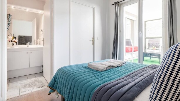 Ein Schlafzimmer mit Bett, Fenster und Blick ins Freie.