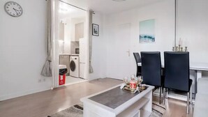 Ein modernes Wohnzimmer mit Essbereich, einer Waschmaschine und einer Wanduhr.