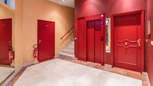 Ein Flur mit roten Türen, einer Treppe und einem Feuerlöscher.