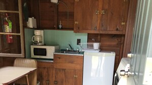 Una cocina compacta con gabinetes de madera, un microondas, un refrigerador y un comedor con mesa y sillas.