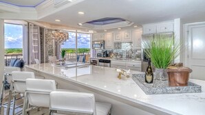 A modern kitchen with a large island, white cabinetry, and a view of the outdoors.