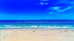 A beach with clear blue water and a sandy shore.
