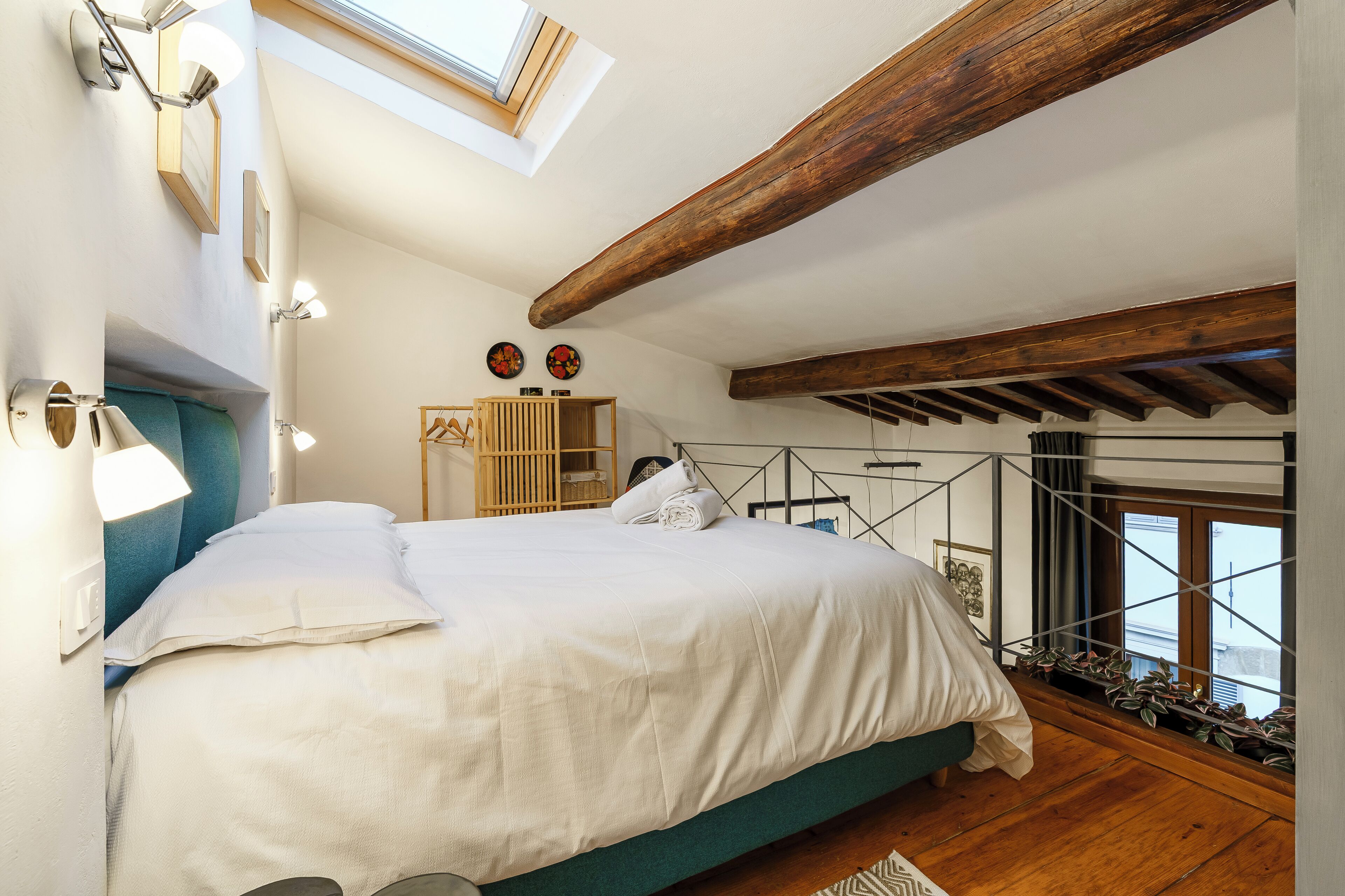 Un dormitorio con una cama grande, tragaluces, vigas de madera y vistas a la ciudad.