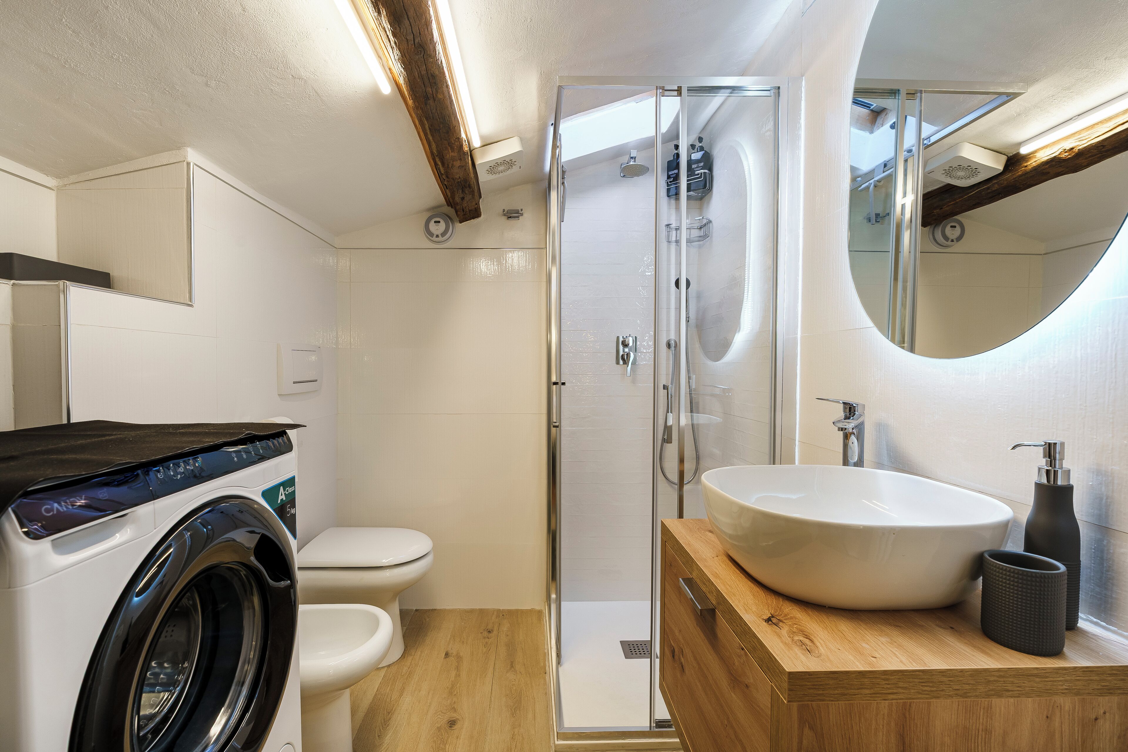 A modern bathroom with a glass-enclosed shower, a built-in sink, and a washing machine.