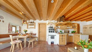 Eine rustikale Küche mit Holzbalken, einem Essbereich mit Bänken und einer kleinen Kochinsel mit Spüle.