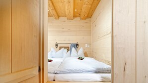 Ein Schlafzimmer einer Holzhütte mit einem Bett, Kissen und einem Nachttisch.