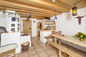 A rustic kitchen with wooden beams, a central island, and a hanging light fixture.