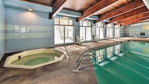 Ein Schwimmbecken mit Holzboden und gefliesten Wänden, mit Whirlpool und Sprungbrett.
