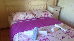A neatly made bed with floral bedding, a purple polka dot blanket, and rolled towels. - Stone house DAN (Sveti Filip i Jakov)