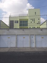 Um edifício com telhado plano, uma janela grande e uma porta com um número.