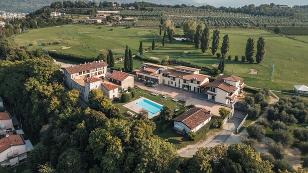 Un grand immeuble à étages, doté d’une piscine, entouré d’une végétation luxuriante et d’un terrain de golf.
