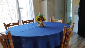 Un comedor con una mesa redonda cubierta con mantel azul, rodeada de sillas de madera.