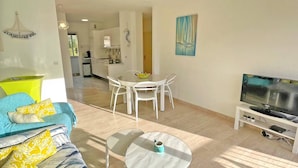 Una sala de estar moderna con un sofá, una mesa de centro, un televisor y un comedor con sillas y una mesa.