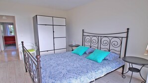 Un dormitorio con cama, armario, silla y una mesita.
