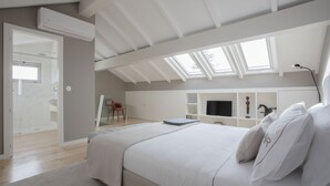 Une chambre dotée d’un grand lit, de fenêtres de toit, d’une télévision et d’un espace bureau.