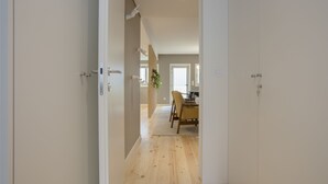 Un couloir au plancher de bois menant à une salle à manger équipée d’une table et de chaises.