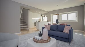 Un salon moderne avec un canapé, une table basse et un escalier menant à la cuisine.