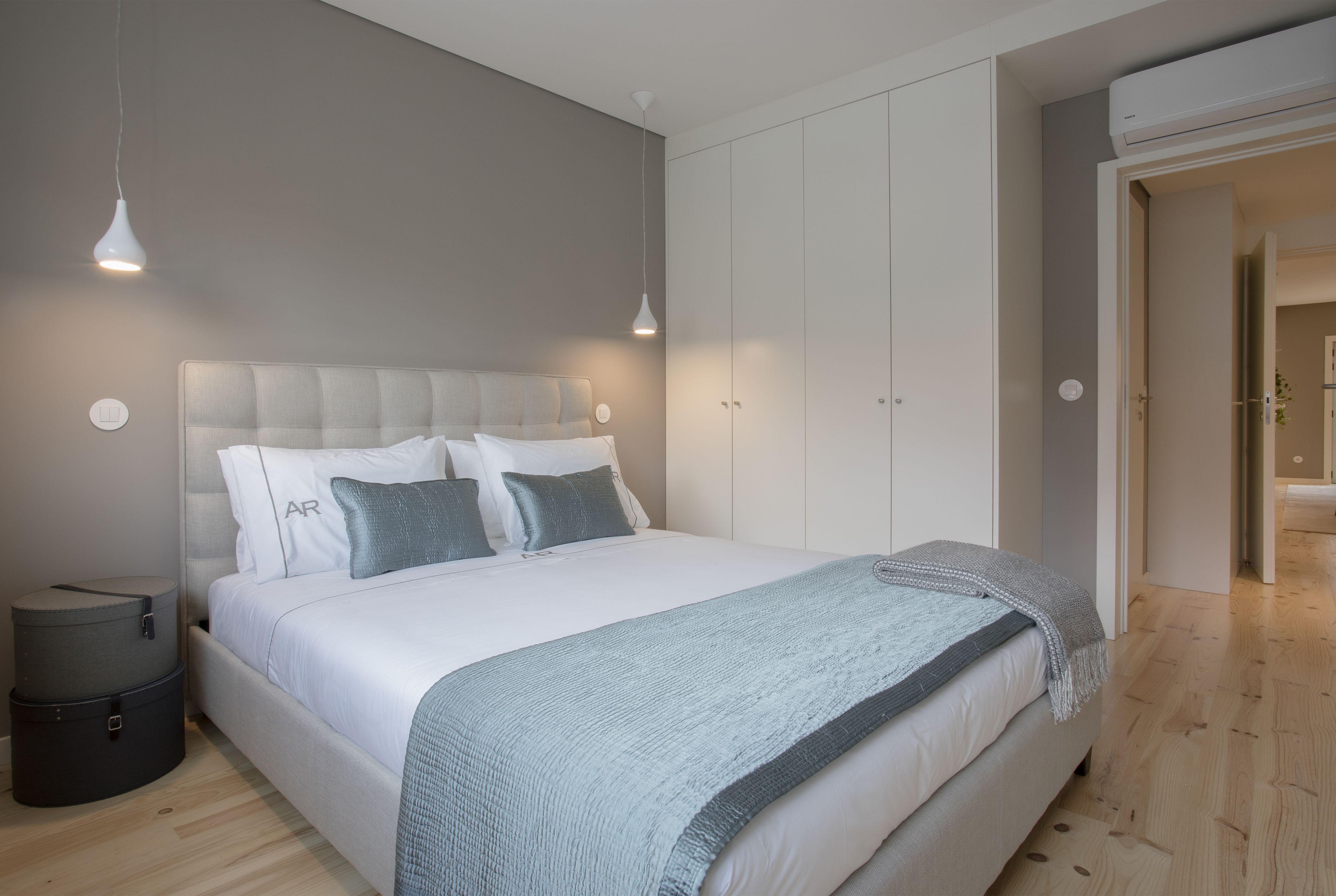 A modern bedroom with a large bed, bedside tables, and a wardrobe.