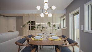 Un coin repas avec une table ronde en bois, dressée pour six personnes, entourée de chaises en bois dotées de coussins bleus.
