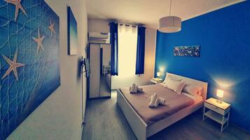 A bedroom with a bed, bedside tables, a lamp, a painting, and a starfish wall design.