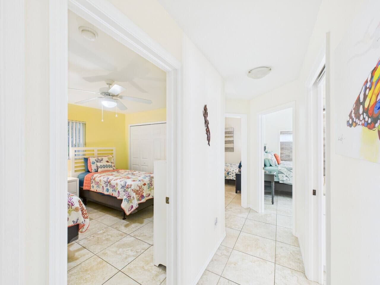 A hallway leading to a bedroom with a bed, a nightstand, and a ceiling fan.