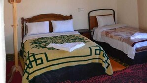 Una habitació amb dos llits, bigues de fusta, una làmpada penjant i un penjallabis.