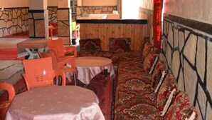 Un restaurant amb una taula comuna llarga, taules individuals i un sofà amb dibuixos.