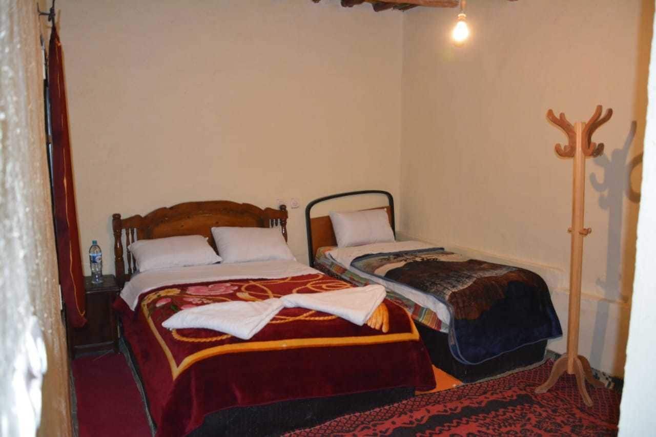 Una habitación pequeña y acogedora con dos camas individuales, un perchero de madera y una alfombra estampada.