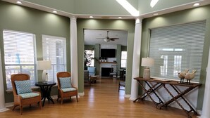 A spacious living room with wooden flooring, a fireplace, and a dining area with two chairs and a table. - Awesome Beach Retreat, 1st Floor, Walking Distance To  the Beach, Pool, Hot Tub (Corpus Christi)