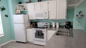 A kitchen with white cabinets, a stove, a sink, and a microwave. - Awesome Beach Retreat, 1st Floor, Walking Distance To  the Beach, Pool, Hot Tub (Corpus Christi)