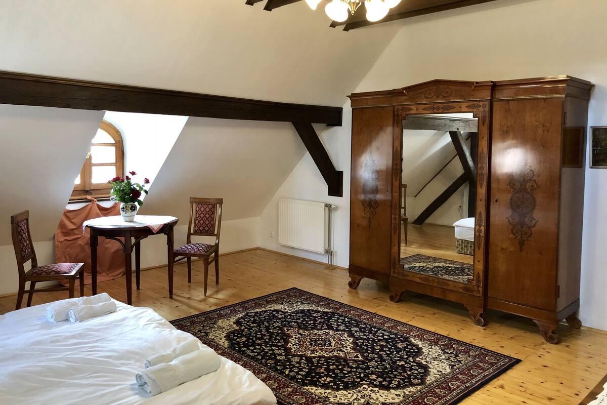 Une chambre à coucher avec un grand lit, une armoire en bois, un bureau avec une chaise et un grand miroir.