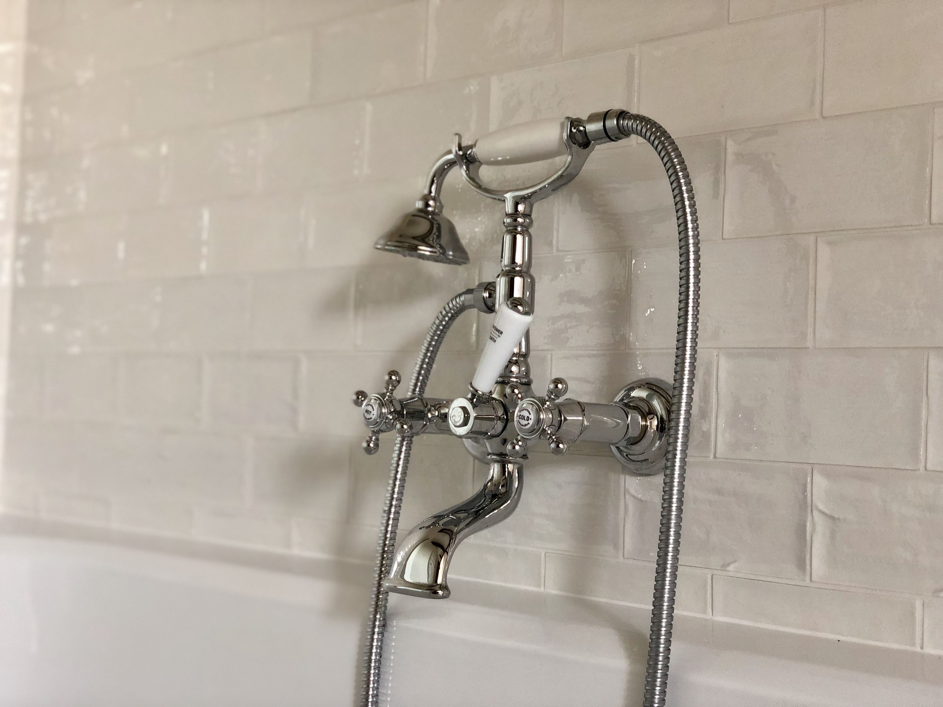 A bathroom with a wall-mounted shower and a bathtub.