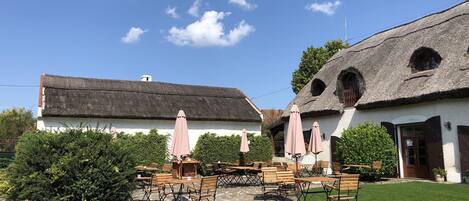 A courtyard with stone flooring, wooden benches, and pink umbrellas.