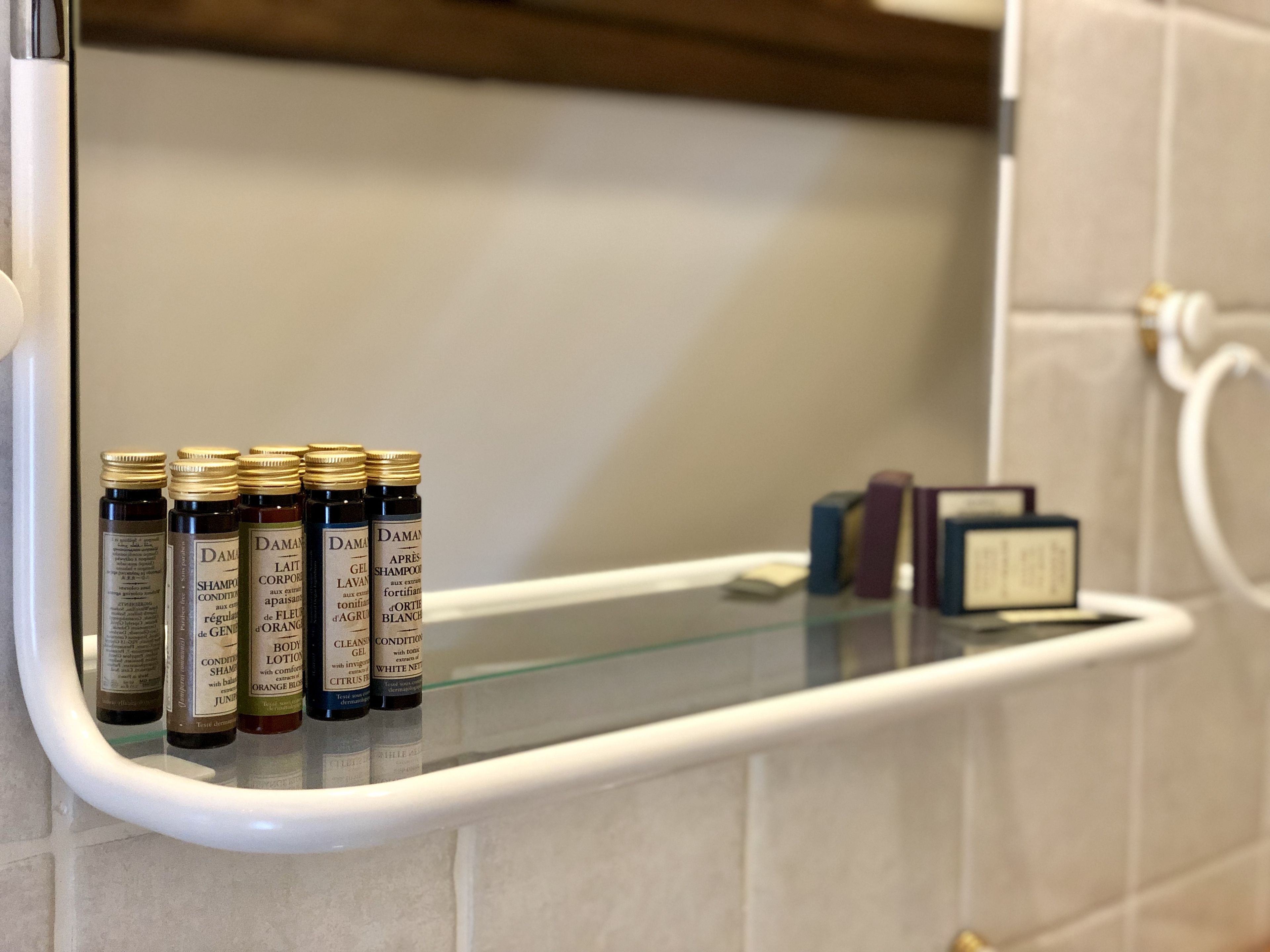 Un estante en el baño con varias botellas de champú y crema corporal.