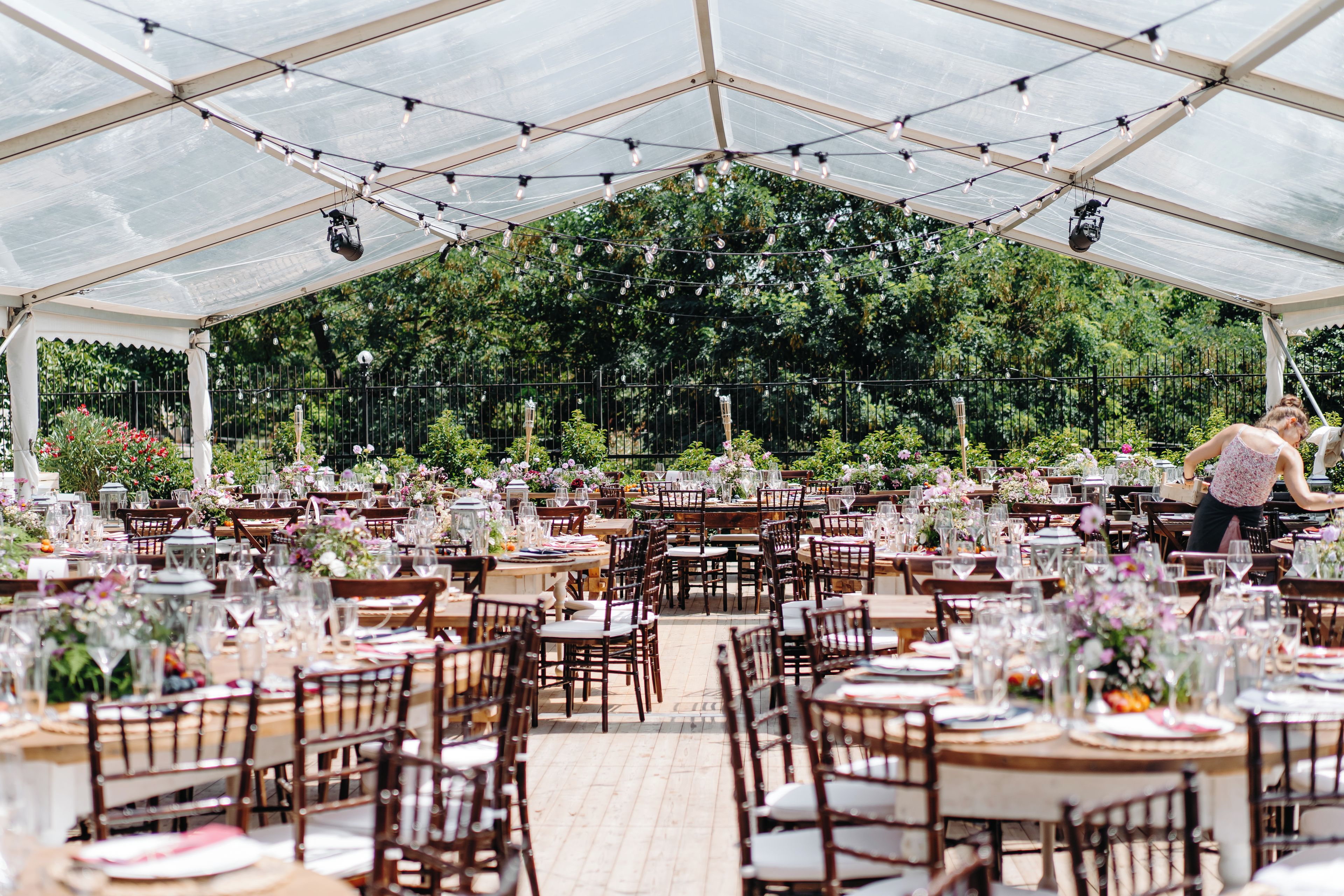 Un espace événementiel intérieur, aménagé avec des tables pour les repas, et entouré de verdure.