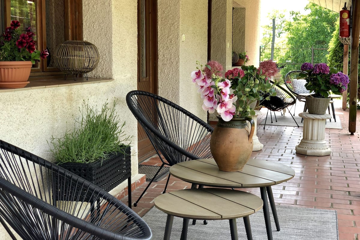 Un patio couvert aménagé avec des chaises en osier, une table et des plantes en pot.