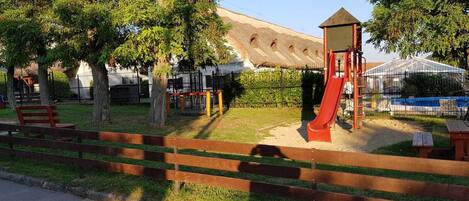 A playground with a slide, benches, and a fenced area.