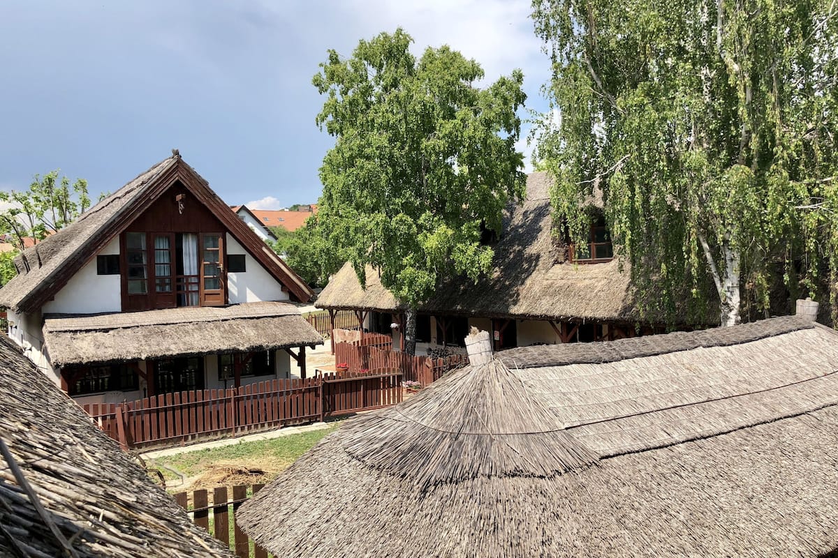 Un village traditionnel avec des bâtiments aux toits de chaume et des clôtures en bois.