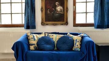 Ein Zimmer mit einem blauen Sofa, einem gerahmten Gemälde und einer Heizung.