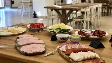 A buffet table with various food items including sliced meats, vegetables, and cheeses.