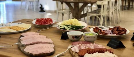 A buffet table with various food items including sliced meats, vegetables, and cheeses.