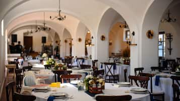 Un restaurante con varias mesas, cada una dispuesta con platos, cubiertos y centros de mesa florales.