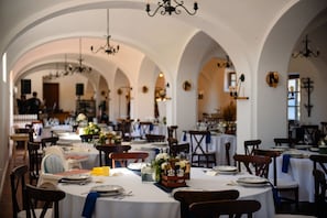 A restaurant with multiple tables, each set with plates, cutlery, and floral centerpieces. - The Houses of History - anno 1830 (Tihany)
