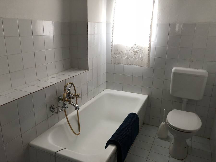 A bathroom with a white bathtub, a toilet, and a shower area.