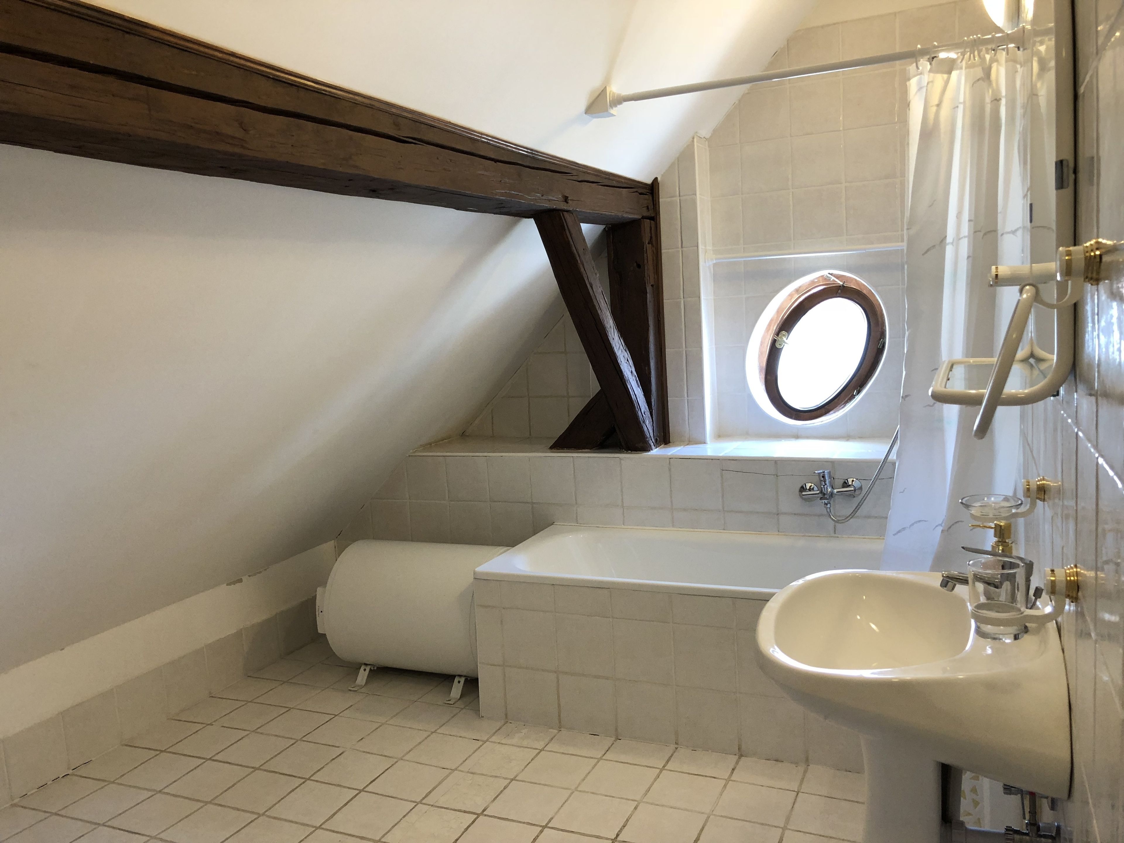 Pieni, moderni kylpyhuone, jossa on wc, pesuallas ja kylpyamme.