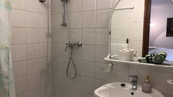 Un baño con ducha, lavamanos y espejo.