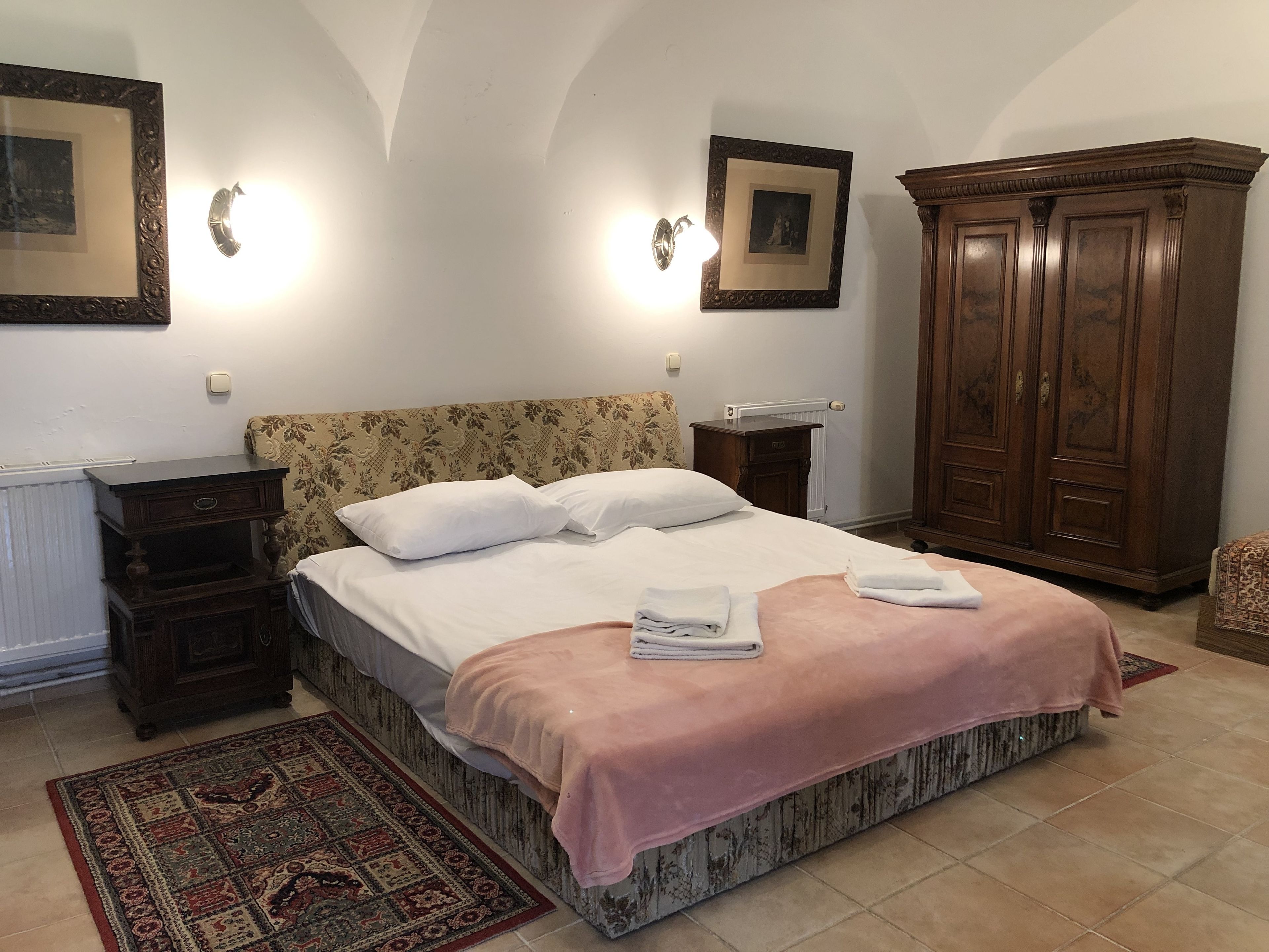 A bedroom with a bed, nightstands, a wardrobe, and a patterned rug.