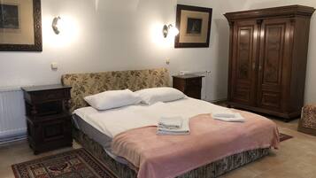 A bedroom with a bed, nightstands, a wardrobe, and a patterned rug.