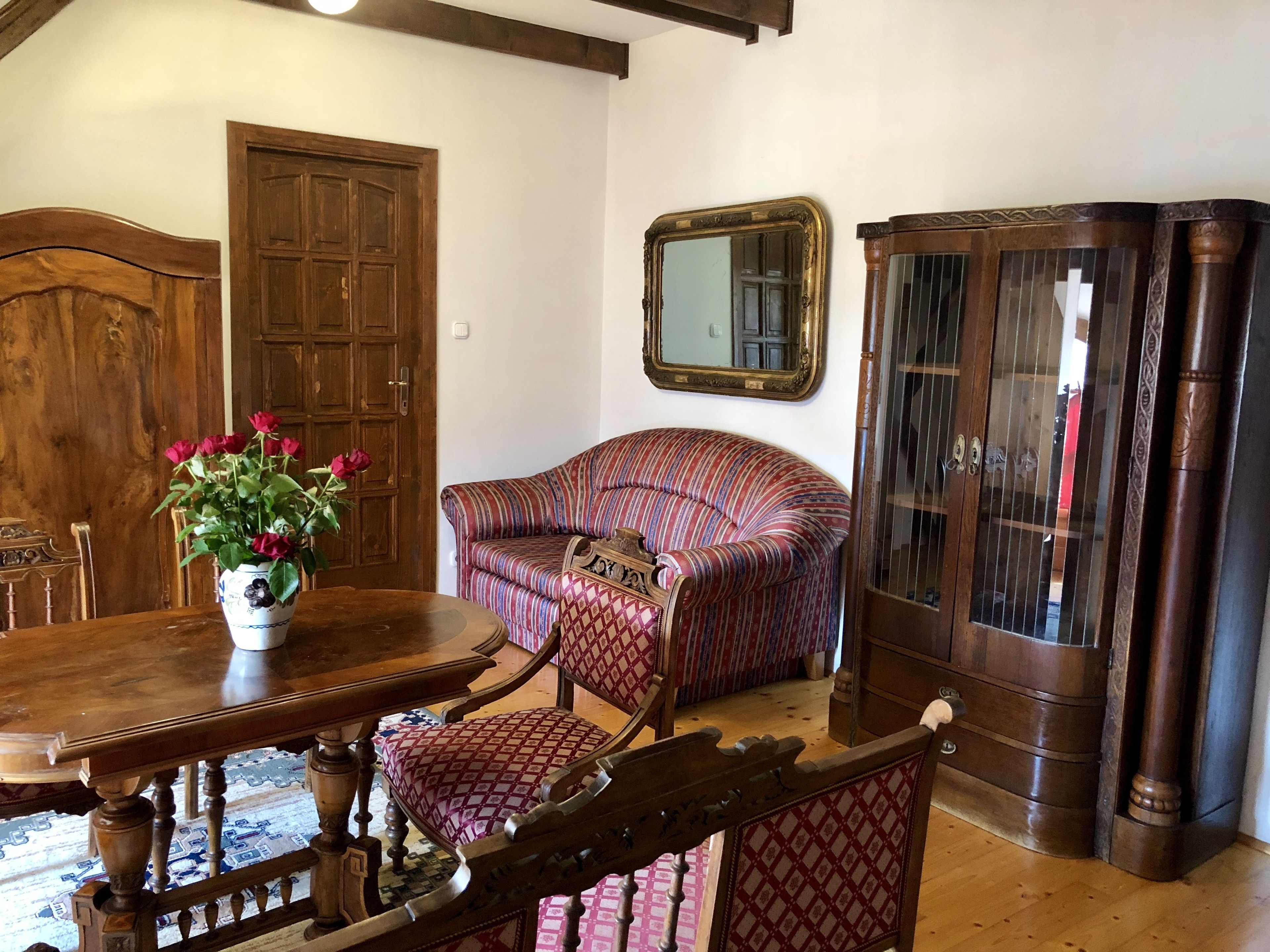 A room with a wooden dining table, a sofa, and a cabinet.