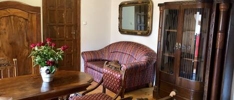 A room with a wooden dining table, a sofa, and a cabinet.